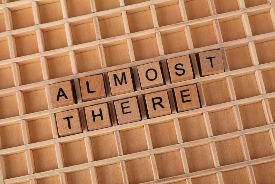 3 Companies That Secretly Own Almost Everything — Wooden letter tiles spelling 'Almost There' on a wooden grid, conveying pro