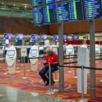 Airlines Profit Beyond Ticket Sales — Busy airport terminal interior with flight information displays and check-in kiosks.