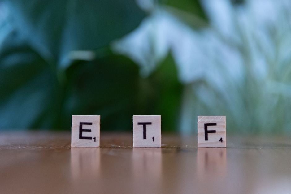 Boring Index Funds Beat Wall Street — Scrabble tiles spelling ETF on a wooden surface with blurred green background.
