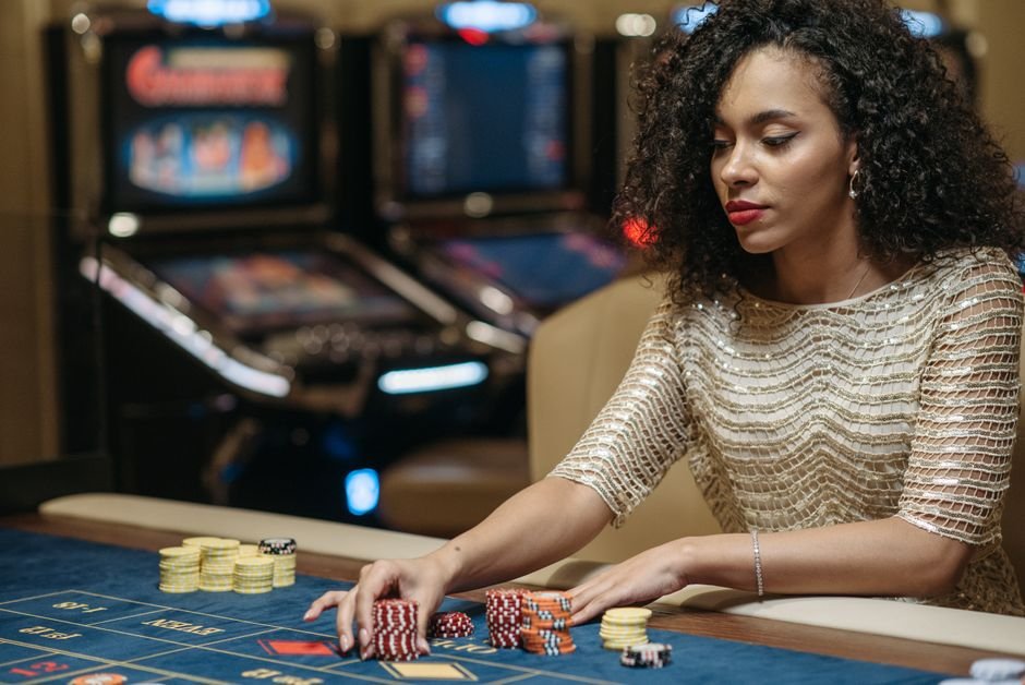 Casinos Engineer Losses Down to the Carpet — Elegant African American woman betting at casino gaming table with chips.