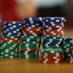 Casinos Engineer Losses Down to the Carpet — A close-up view of colorful stacked poker chips on a wooden table, perfect for c