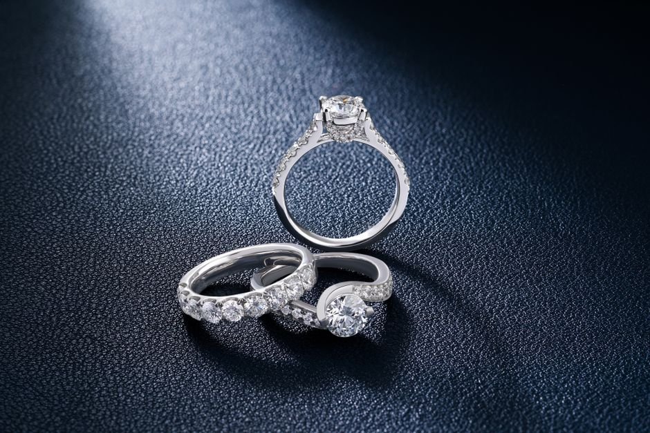 De Beers Engineered Diamond Scarcity — Close-up of luxurious diamond engagement and wedding rings on a textured surface, show