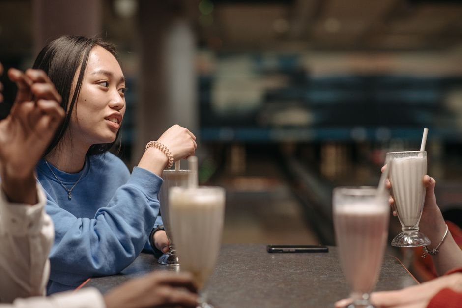 From Milkshake Salesman to Global — Group of friends enjoying milkshakes indoors at a café, engaging in conversation.