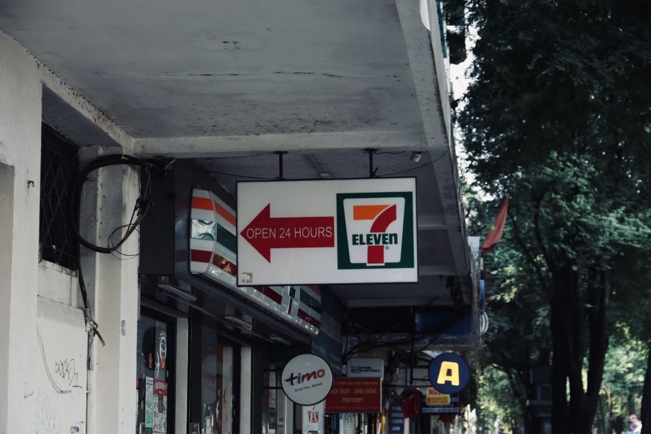 From One Store to Global — 7-Eleven convenience store sign and storefront, open 24 hours in an urban setting.