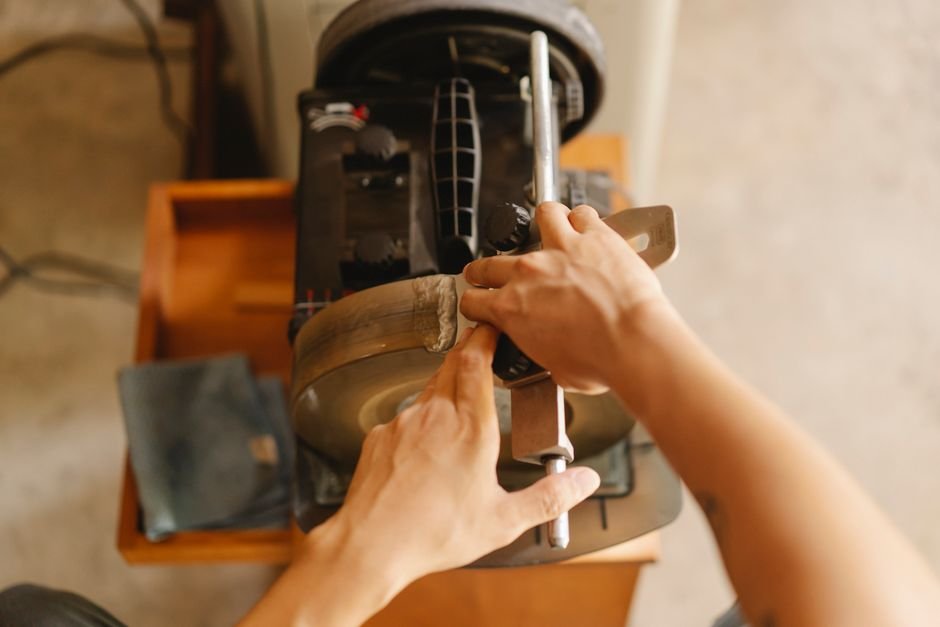 From Rags to Steel — From above of anonymous craftsman using grinding wheel to sharpen metal knife while working at special i