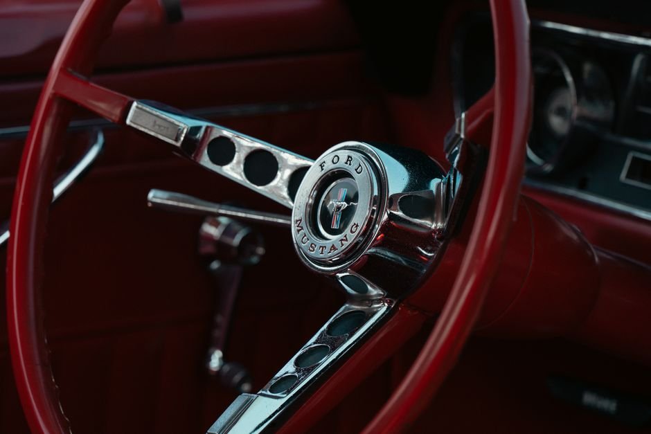 Henry Ford — Detailed view of a vintage red Ford Mustang steering wheel interior.