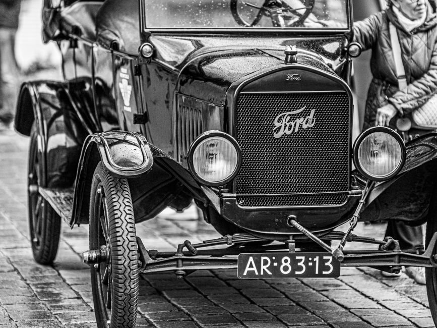 Henry Ford — Classic Ford Model T car displayed on cobbled street, black and white photo.