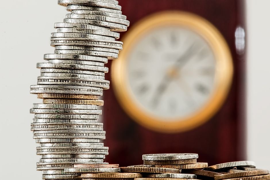 Hidden Power of Compound Interest — A close-up image of stacked coins with a blurred clock, symbolizing time and money relati