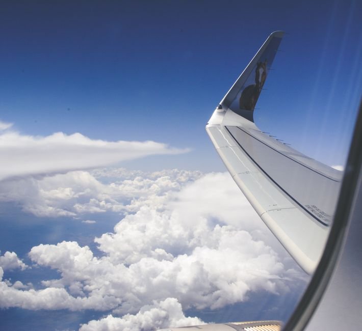 Pan Am Vanished From the Skies — View from airplane window showcasing a wing above fluffy clouds during daylight.