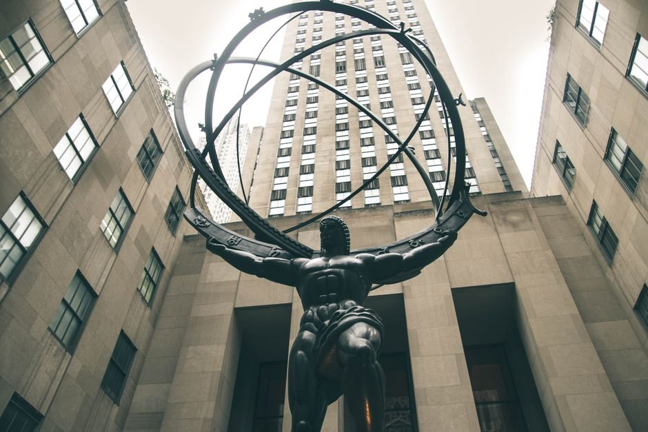 Paradox of Rockefeller — Low angle view of Atlas statue with skyscrapers at Rockefeller Center, New York City.