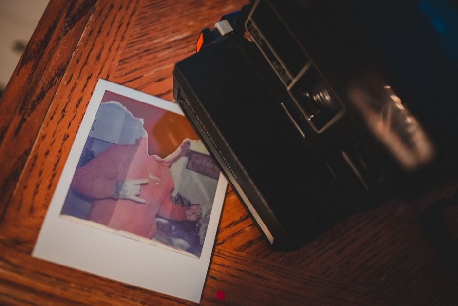 Polaroid Fell Twice After Instant Glory — Top view of instant old fashioned camera placed on wooden table near torn picture
