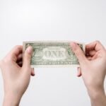 Quiet Power of Dollar‑Cost Averaging — A close-up image of hands holding a one dollar bill, symbolizing finance and economy.
