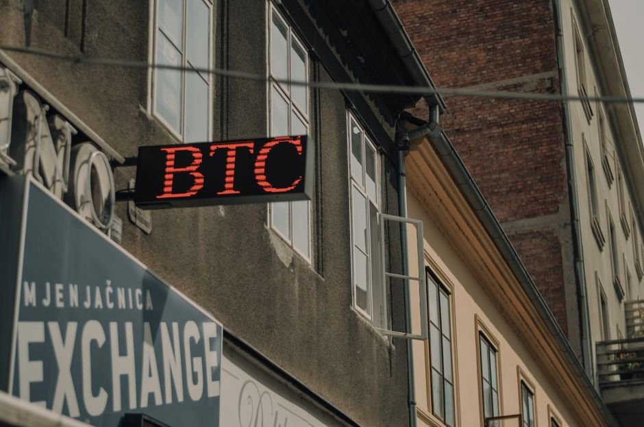 cryptocurrency finance trading collapse — Exterior of a building featuring a prominent BTC and exchange sign, indicating a cr