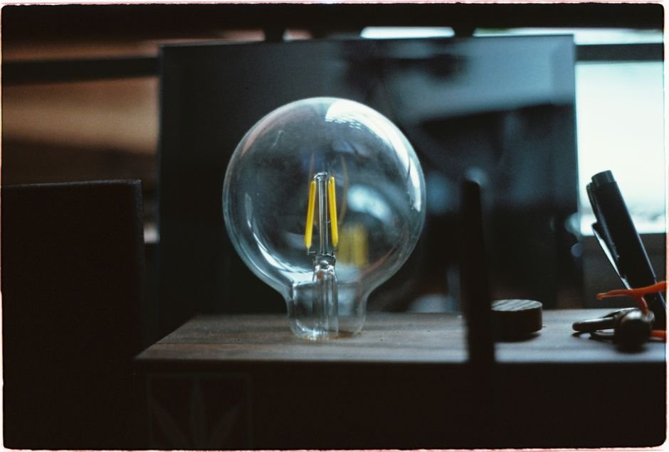 the Phoebus Cartel Engineered Light‑Bulb Death — A detailed close-up of a traditional light bulb placed on a workbench in a w